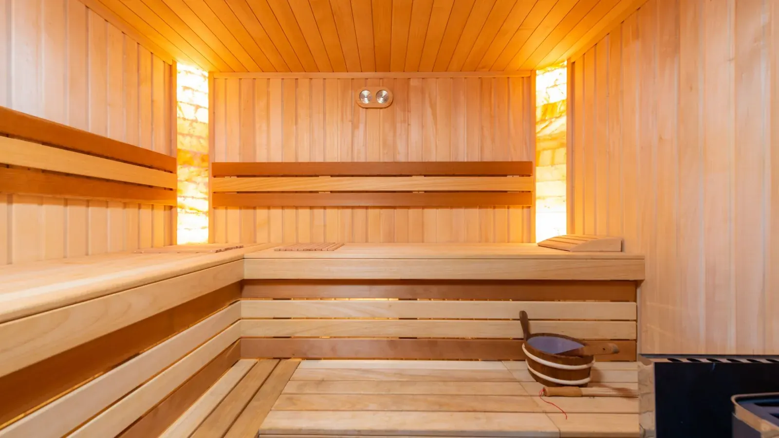 A pale wood sauna interior with warm amber light glowing through the panels.