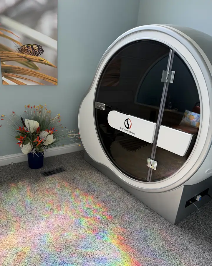 The OxyBoost cabin: a rounded white shell with a large tinted door, beside a vase of flowers.