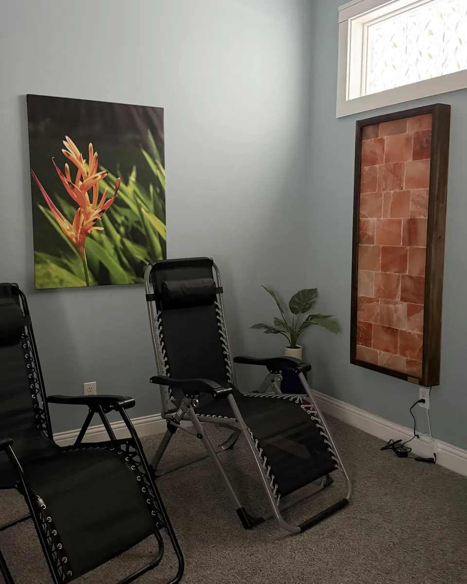 Two reclining chairs in the Salt Lounge beside a backlit Himalayan salt panel, with daylight through a frosted window.