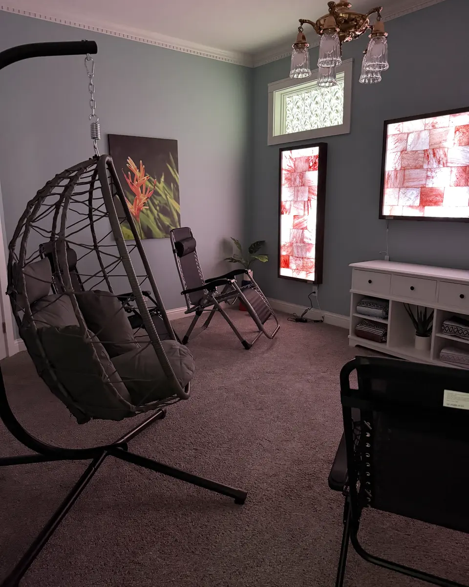 The salt lounge at My Oasis 502: a hanging egg chair and a reclining zero-gravity chair facing backlit Himalayan salt panels.